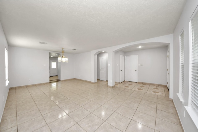 4310 Lucas Trace Ct, Houston, TX 77066 - empty room featuring arched walkways, light tile patterned flooring, a chandelier, a textured ceiling, and baseboards