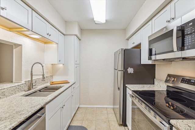4631 Wild Indigo St Unit 575, Houston, TX 77027 - kitchen with appliances with stainless steel finishes, a sink, white cabinetry, baseboards, and a textured wall
