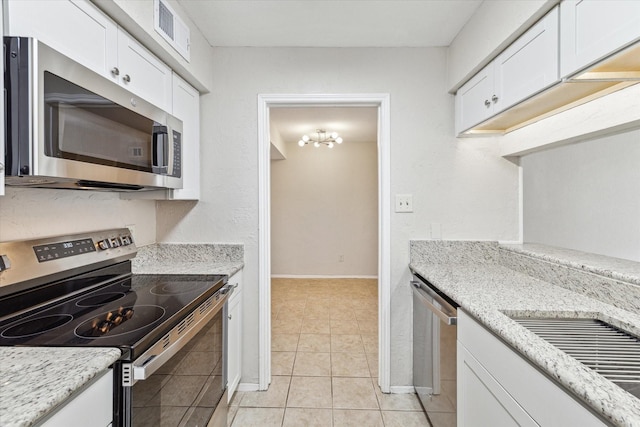 4631 Wild Indigo St Unit 575, Houston, TX 77027 - kitchen featuring appliances with stainless steel finishes, white cabinets, light tile patterned floors, and baseboards