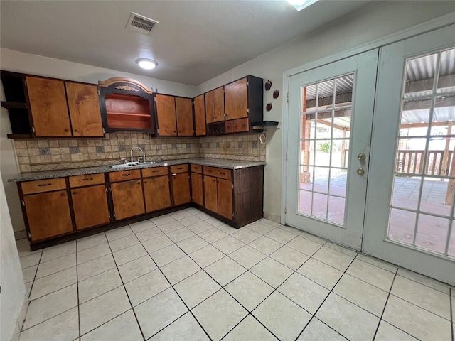 6402 Belarbor St, Houston, TX 77087 - kitchen featuring open shelves, a sink, brown cabinets, tasteful backsplash, and light tile patterned floors
