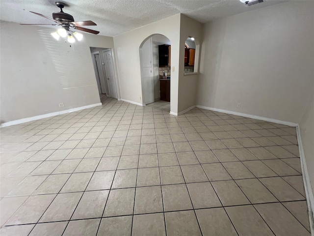 6402 Belarbor St, Houston, TX 77087 - spare room with ceiling fan, a textured ceiling, baseboards, arched walkways, and light tile patterned floors