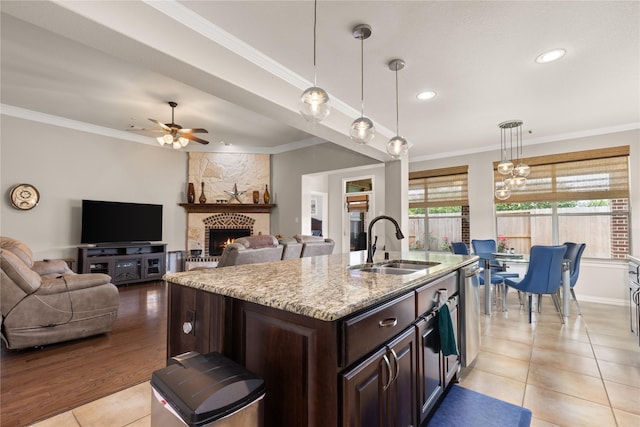 25019 Bahme Springs Ln, Porter, TX 77365 - kitchen with a sink, light stone countertops, ornamental molding, dark brown cabinets, and light tile patterned floors