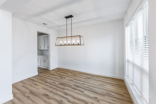 4131 Creek Shore Ln, Fulshear, TX 77441 - unfurnished dining area featuring light wood-style floors, baseboards, and a chandelier