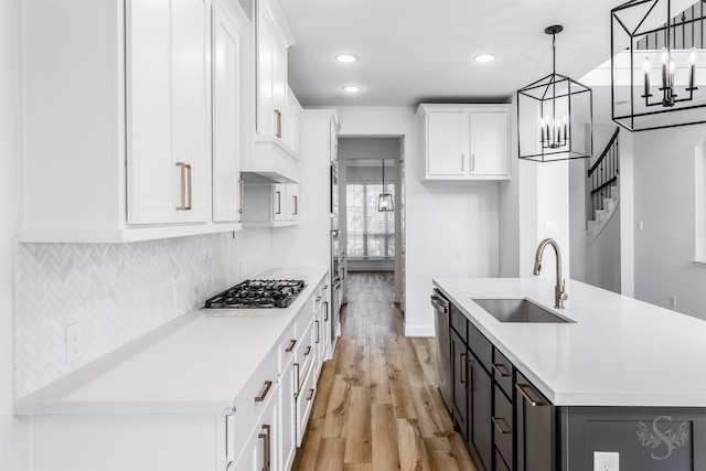 4131 Creek Shore Ln, Fulshear, TX 77441 - kitchen with a sink, appliances with stainless steel finishes, a chandelier, light wood-type flooring, and white cabinets
