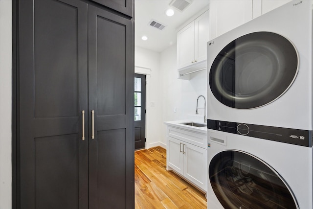 1514 31st St, Galveston, TX 77550 - washroom with stacked washer / dryer, cabinet space, light wood-style floors, recessed lighting, and baseboards