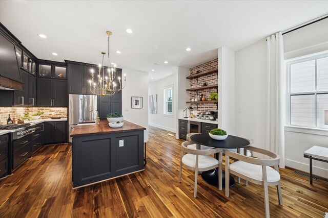 1514 31st St, Galveston, TX 77550 - kitchen featuring stainless steel appliances, butcher block counters, decorative backsplash, a chandelier, and an island with sink