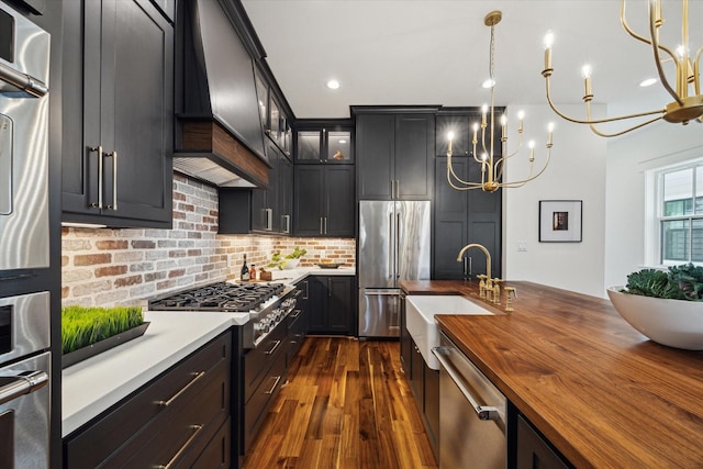 1514 31st St, Galveston, TX 77550 - kitchen featuring butcher block countertops, appliances with stainless steel finishes, dark wood-type flooring, a sink, and tasteful backsplash