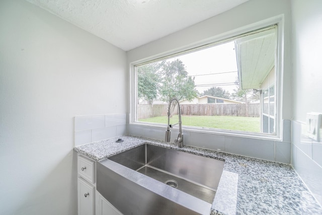 5229 W 43rd St, Houston, TX 77092 - kitchen with a sink, white cabinetry, light stone counters, vaulted ceiling, and a textured ceiling