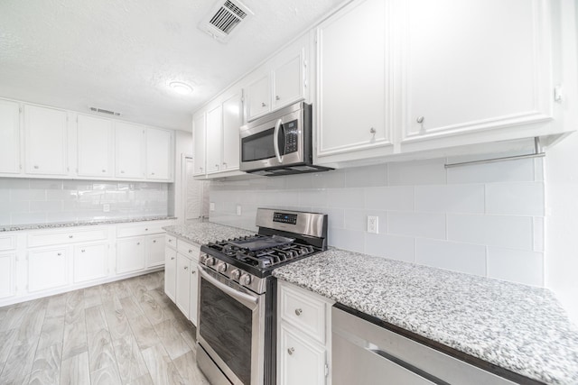 5229 W 43rd St, Houston, TX 77092 - kitchen with appliances with stainless steel finishes, tasteful backsplash, white cabinets, light stone counters, and a textured ceiling