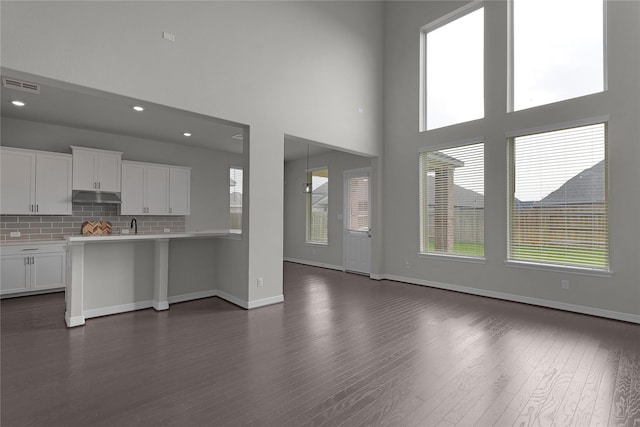 6026 Lake Bridge Ln, Manvel, TX 77578 - kitchen with under cabinet range hood, open floor plan, dark wood-type flooring, white cabinets, and light countertops