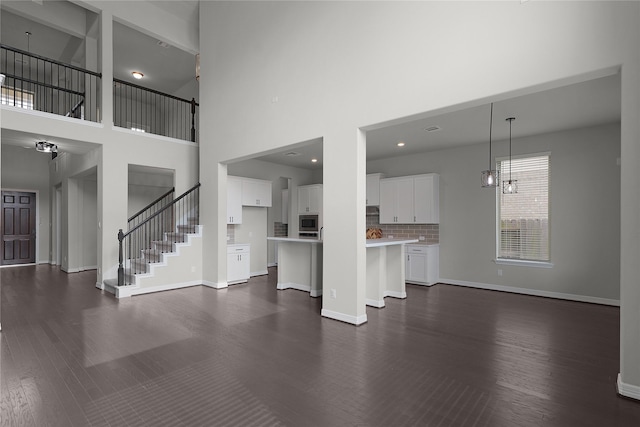6026 Lake Bridge Ln, Manvel, TX 77578 - unfurnished living room with a high ceiling, dark wood finished floors, baseboards, stairs, and a chandelier