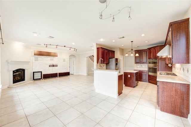 14330 Ayers Rock Rd, Sugar Land, TX 77498 - kitchen with open floor plan, wall chimney range hood, stainless steel appliances, track lighting, and backsplash