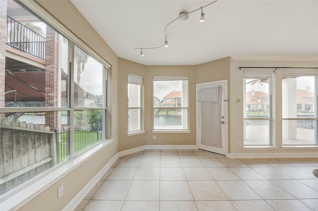 14330 Ayers Rock Rd, Sugar Land, TX 77498 - unfurnished sunroom featuring tile patterned flooring, a water view, baseboards, and rail lighting