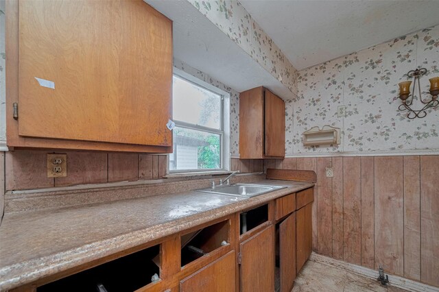 13326 Sundale Rd, Houston, TX 77038 - kitchen featuring wallpapered walls, a wainscoted wall, brown cabinets, wood walls, and light countertops