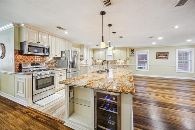 7506 Dearborn St, Houston, TX 77055 - kitchen with appliances with stainless steel finishes, wine cooler, a sink, light wood finished floors, and a kitchen island with sink