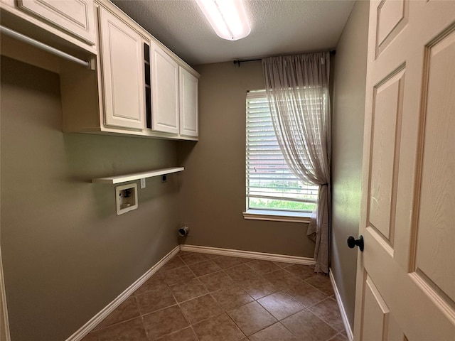 243 Fantasy Ln, Montgomery, TX 77356 - washroom with washer hookup, a textured ceiling, baseboards, dark tile patterned flooring, and cabinet space