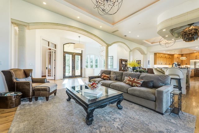 115 Hidden Hills Dr, Spicewood, TX 78669 - living area featuring ornate columns, a raised ceiling, recessed lighting, a chandelier, and light wood finished floors