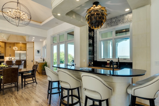 115 Hidden Hills Dr, Spicewood, TX 78669 - kitchen with built in fridge, light wood-type flooring, a chandelier, dark countertops, and plenty of natural light