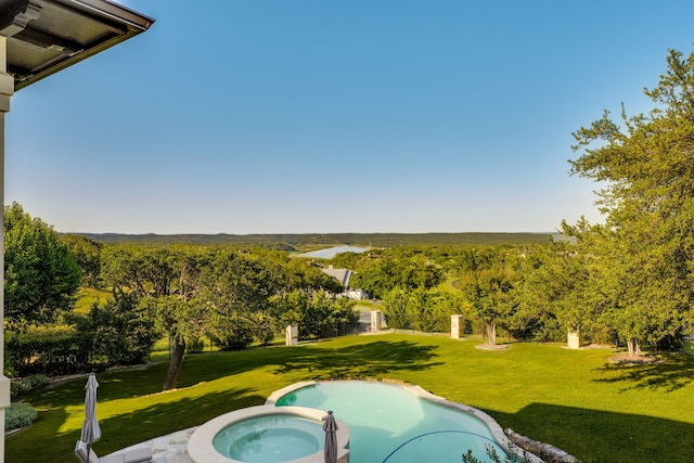115 Hidden Hills Dr, Spicewood, TX 78669 - view of swimming pool featuring a yard, a pool with connected hot tub, and a wooded view