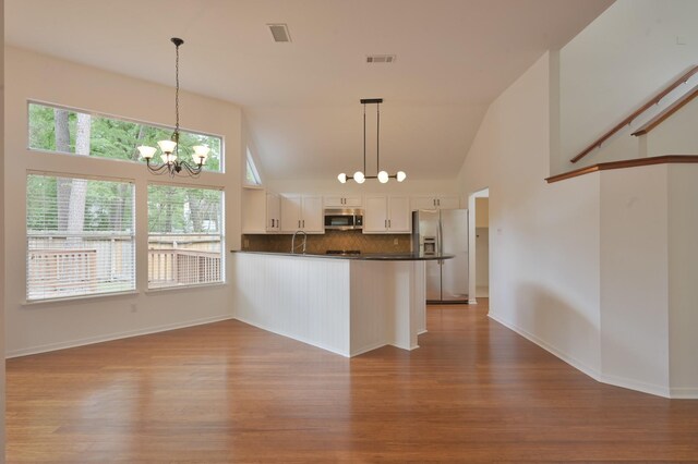 3 Shallow Pond Ct, The Woodlands, TX 77381 - kitchen with appliances with stainless steel finishes, a chandelier, wood finished floors, dark countertops, and tasteful backsplash
