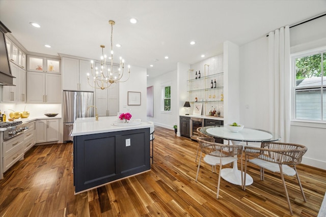 1518 31st St, Galveston, TX 77550 - kitchen featuring stainless steel appliances, beverage cooler, dark wood finished floors, light countertops, and a kitchen island with sink