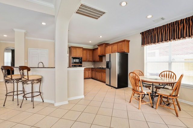 12822 Winding Manor Dr, Houston, TX 77044 - kitchen with fridge with ice dispenser, black microwave, brown cabinets, ornamental molding, and tasteful backsplash