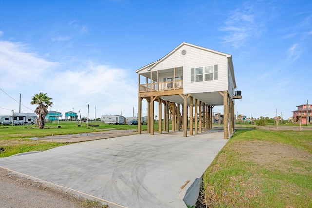 1023 N Bay St, Gilchrist, TX 77617 - coastal home with a carport, concrete driveway, covered porch, and a front lawn