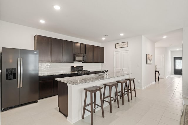 12022 Fletching Stone Ln, Houston, TX 77044 - kitchen with stainless steel refrigerator with ice dispenser, black microwave, range with gas cooktop, a breakfast bar area, and dark brown cabinets