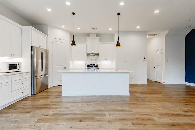7810 Kenton St, Houston, TX 77028 - kitchen with high quality fridge, white microwave, recessed lighting, an island with sink, and white cabinetry