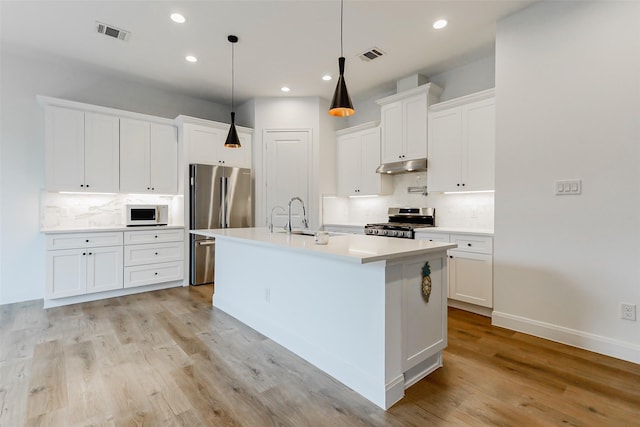 7810 Kenton St, Houston, TX 77028 - kitchen with appliances with stainless steel finishes, under cabinet range hood, decorative backsplash, white cabinets, and recessed lighting