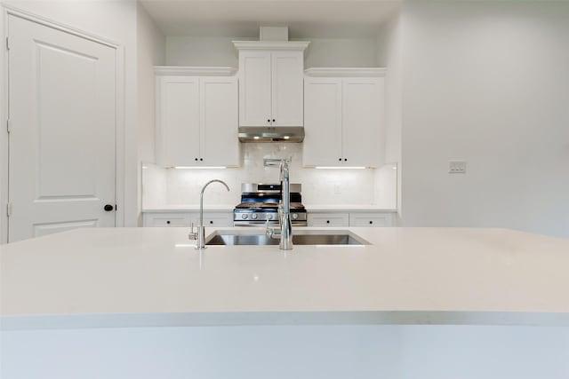 7810 Kenton St, Houston, TX 77028 - kitchen featuring under cabinet range hood, decorative backsplash, white cabinets, light countertops, and stainless steel gas range