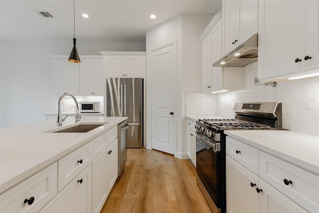 7810 Kenton St, Houston, TX 77028 - kitchen featuring appliances with stainless steel finishes, a sink, under cabinet range hood, white cabinets, and light countertops