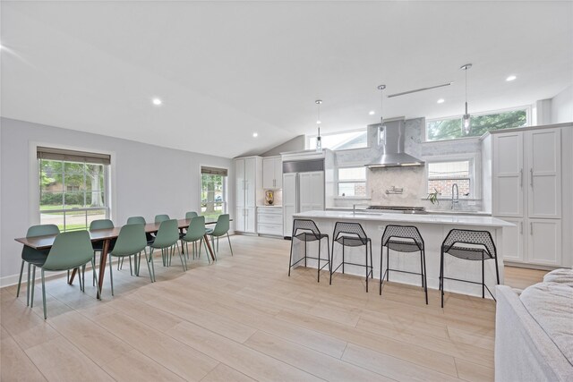 18215 Hereford Ln, Houston, TX 77058 - kitchen featuring wall chimney exhaust hood, light countertops, tasteful backsplash, a sink, and a kitchen breakfast bar