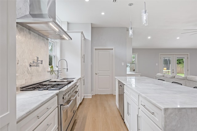 18215 Hereford Ln, Houston, TX 77058 - kitchen with stainless steel appliances, wall chimney range hood, open floor plan, light wood-style flooring, and light stone counters