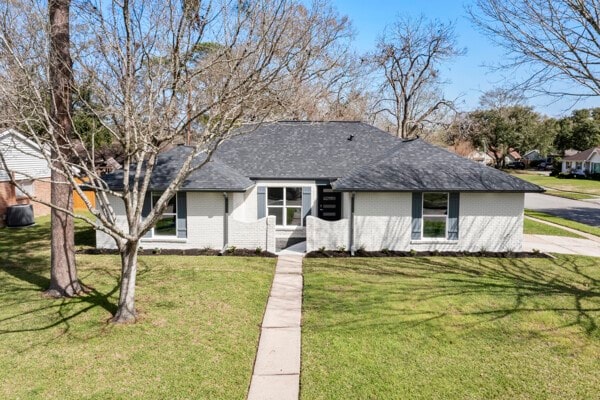 10719 Carlota Ct, Houston, TX 77096 - view of front facade featuring brick siding, a front yard, and a shingled roof