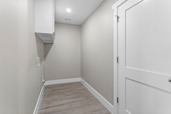 10719 Carlota Ct, Houston, TX 77096 - laundry area featuring baseboards and light wood-style floors