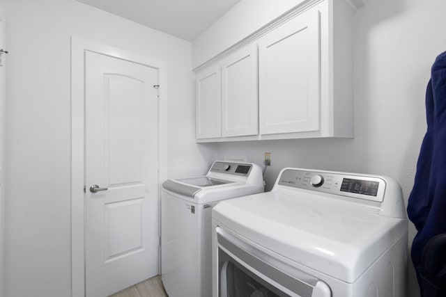 9222 New Forest Rd, Spring, TX 77379 - laundry room featuring washing machine and clothes dryer, cabinet space, and light wood finished floors