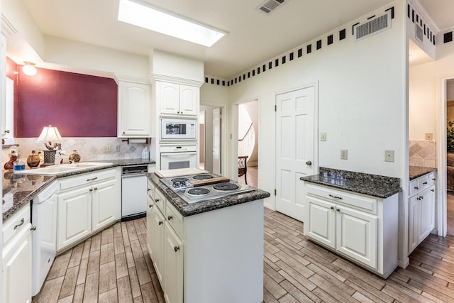 18 Village Hill Dr, Conroe, TX 77304 - kitchen with white appliances, tasteful backsplash, light wood-type flooring, white cabinets, and a center island