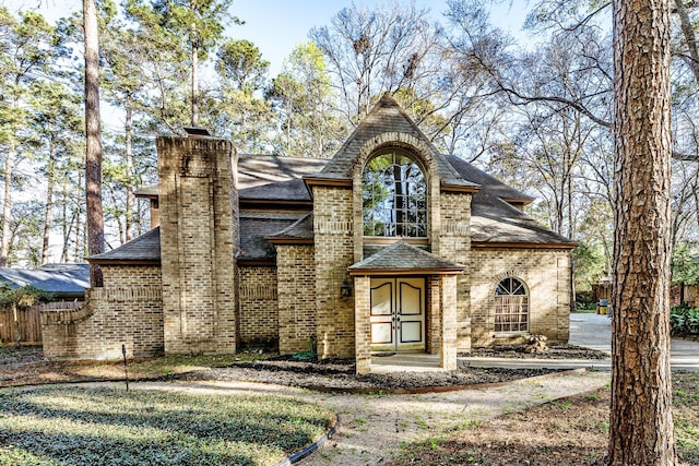 18 Village Hill Dr, Conroe, TX 77304 - view of front facade with a shingled roof, brick siding, and a chimney