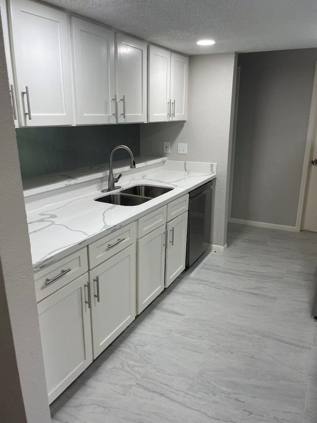 19414 Leafwood Ln, Houston, TX 77084 - kitchen with a sink, a textured ceiling, light stone counters, white cabinetry, and baseboards