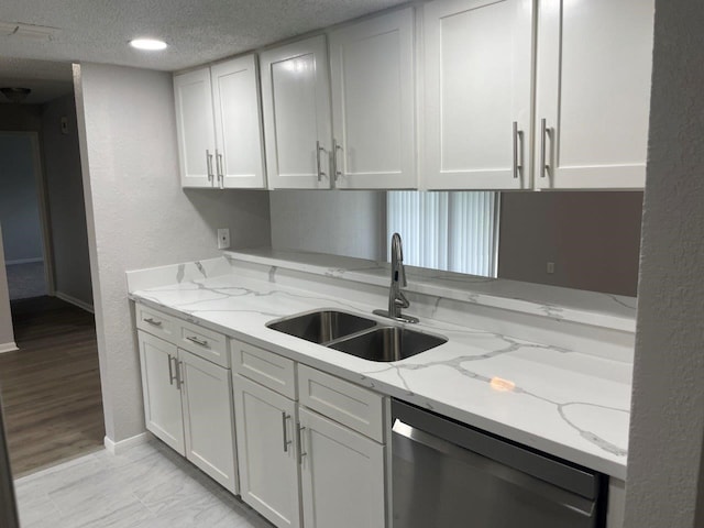 19414 Leafwood Ln, Houston, TX 77084 - kitchen with stainless steel dishwasher, a sink, a textured ceiling, white cabinetry, and baseboards