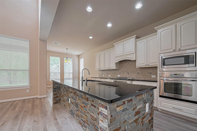 5442 Jackson Park Ln, Katy, TX 77494 - kitchen featuring stainless steel appliances, a sink, light wood-style floors, dark stone counters, and tasteful backsplash