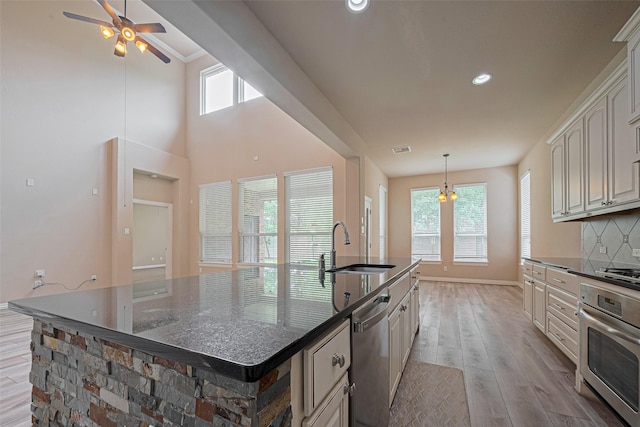 5442 Jackson Park Ln, Katy, TX 77494 - kitchen featuring appliances with stainless steel finishes, a sink, light wood-type flooring, a large island, and a ceiling fan