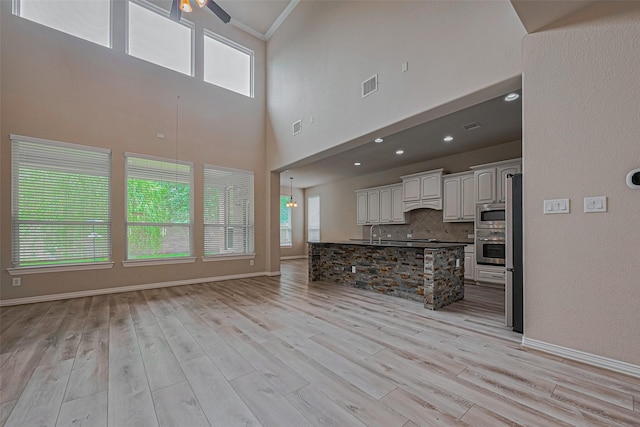 5442 Jackson Park Ln, Katy, TX 77494 - unfurnished living room featuring a sink, a ceiling fan, light wood-type flooring, baseboards, and a high ceiling