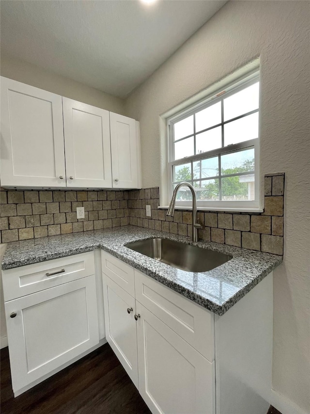 527 W 4th St, Freeport, TX 77541 - kitchen with a sink, tasteful backsplash, light stone countertops, dark wood-style floors, and white cabinetry