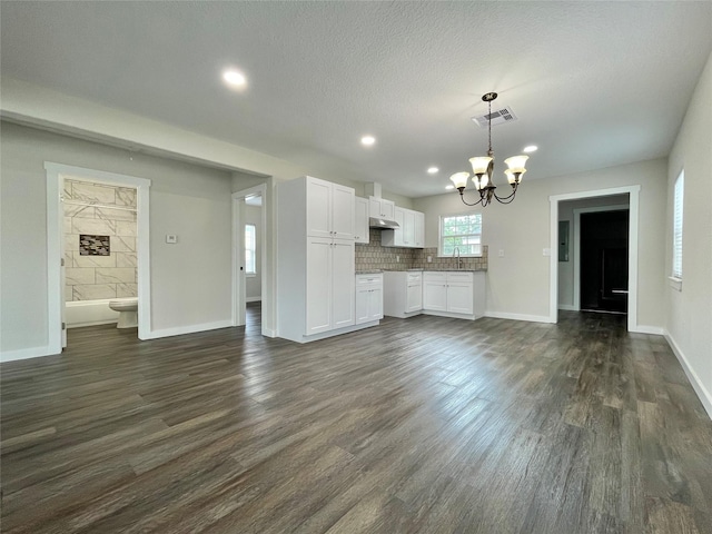 527 W 4th St, Freeport, TX 77541 - unfurnished living room with a chandelier, dark wood-type flooring, baseboards, recessed lighting, and a textured ceiling