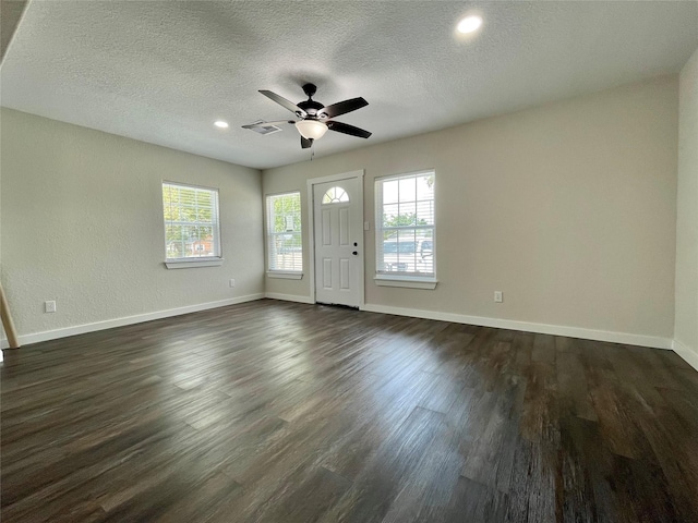 527 W 4th St, Freeport, TX 77541 - unfurnished living room featuring healthy amount of natural light, ceiling fan, dark wood finished floors, baseboards, and a textured ceiling