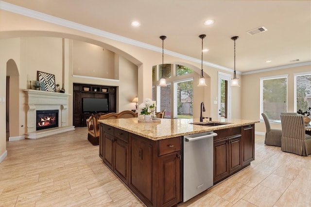 19023 Wild Thornberry Dr, Tomball, TX 77377 - kitchen featuring stainless steel dishwasher, a sink, dark brown cabinets, a glass covered fireplace, and pendant lighting