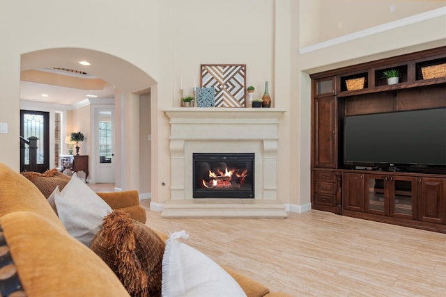 19023 Wild Thornberry Dr, Tomball, TX 77377 - living area featuring arched walkways, ornamental molding, a glass covered fireplace, baseboards, and a towering ceiling