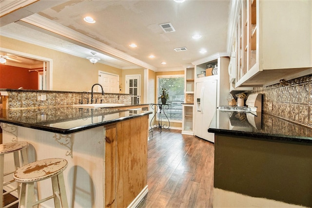 7914 Woodsman Trl, Houston, TX 77040 - kitchen with white refrigerator with ice dispenser, ornamental molding, a sink, a breakfast bar, and backsplash